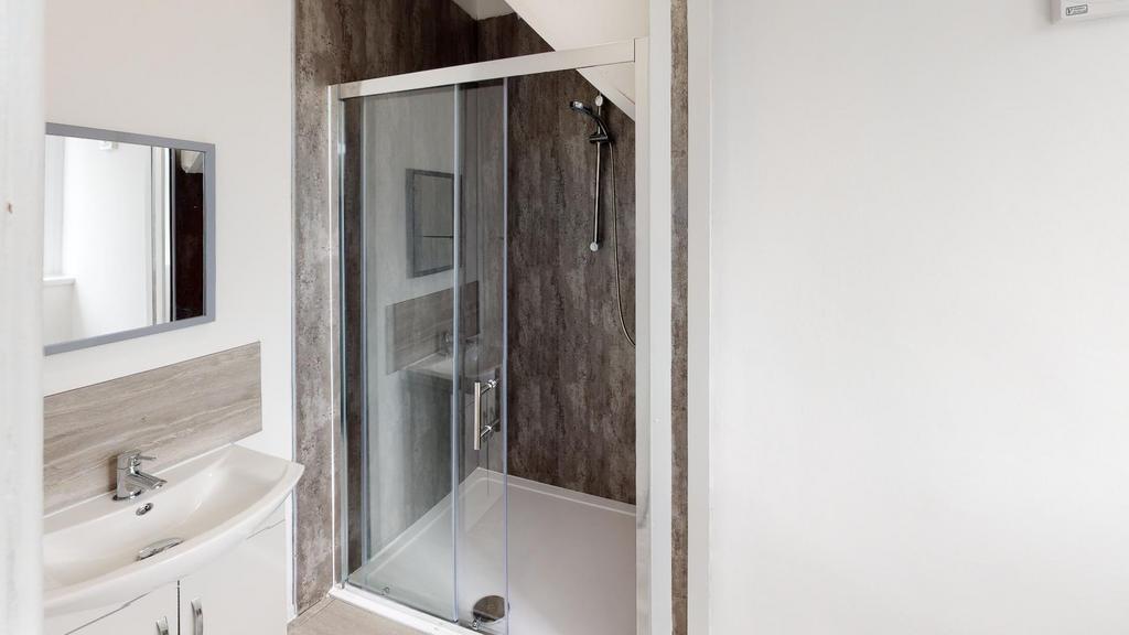 A modern bathroom featuring a spacious shower e...