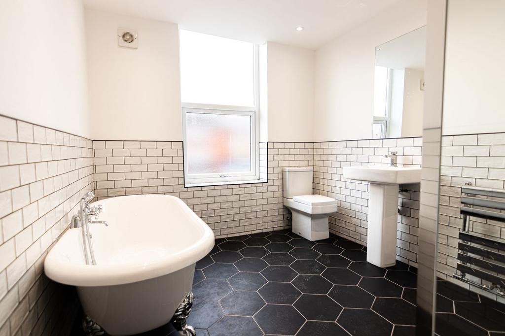 A clean, modern bathroom featuring a freestandi...