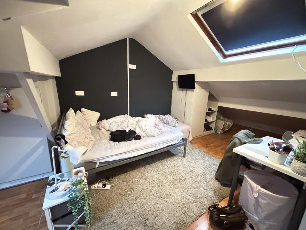 A cozy bedroom featuring a single bed with bedd...