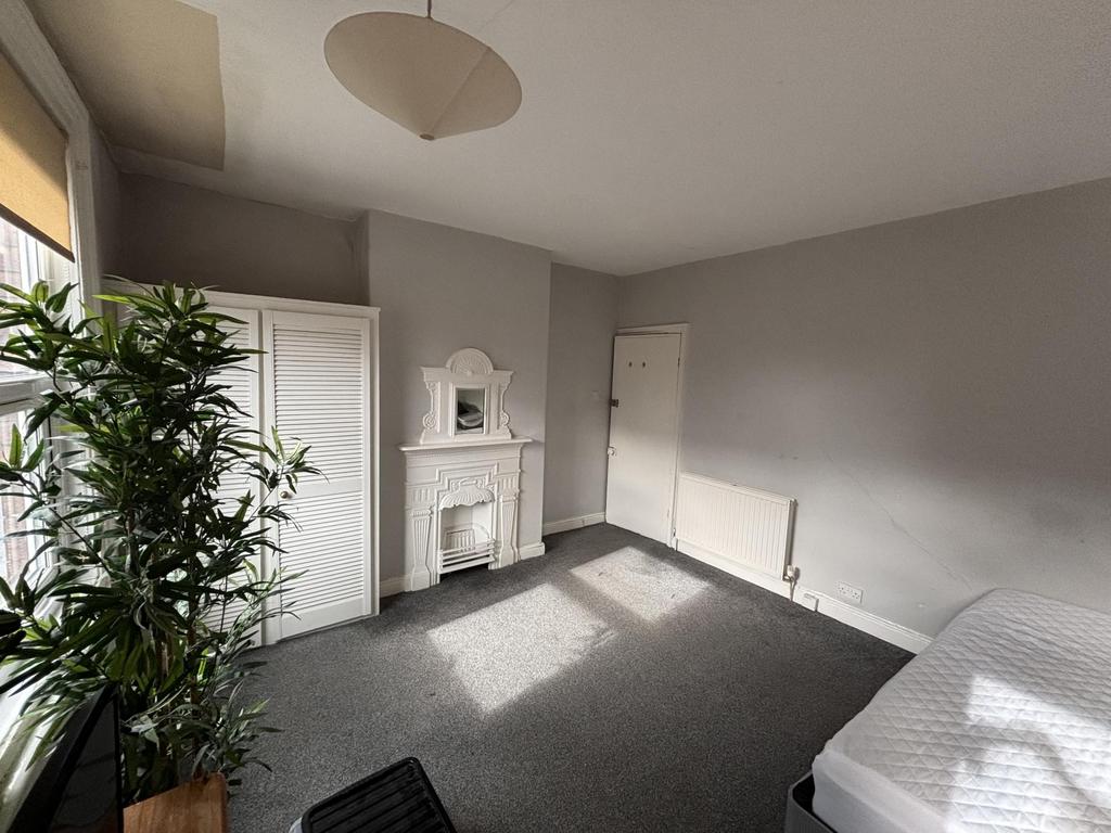 A bright and tidy bedroom featuring a large win...
