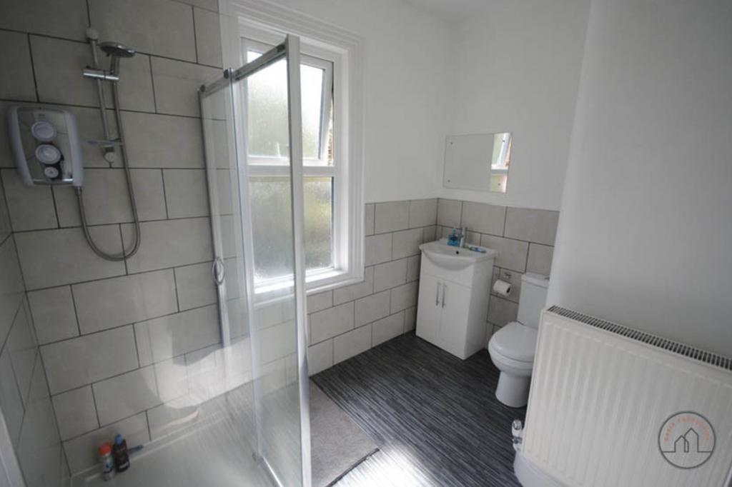 A clean and modern bathroom with a shower unit,...
