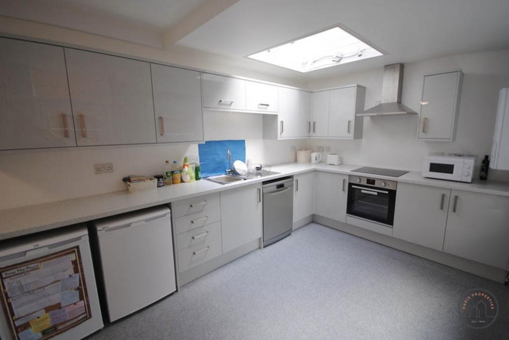 A bright, modern kitchen featuring white cabine...