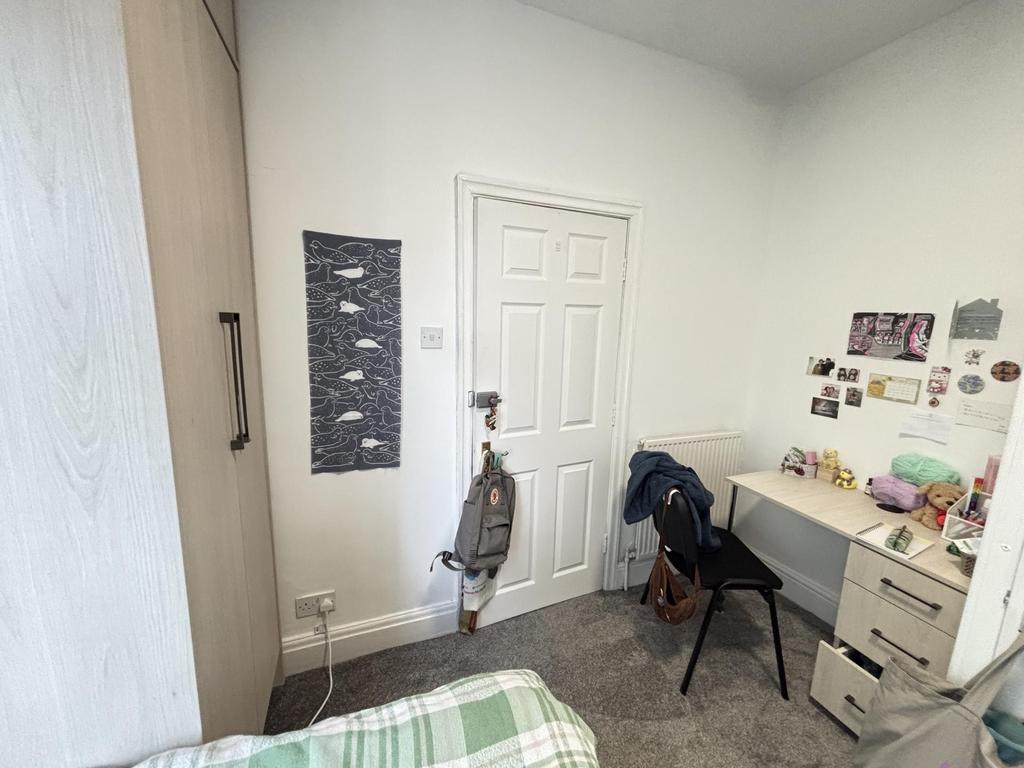 A cozy single bedroom featuring a bed, a desk, ...