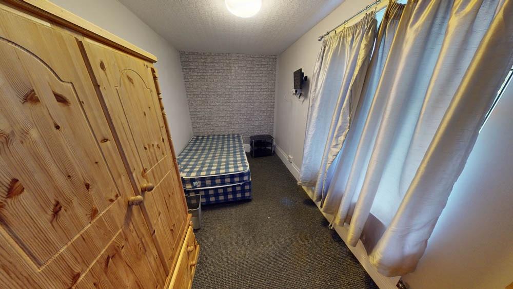 A cozy student bedroom featuring a simple bed a...