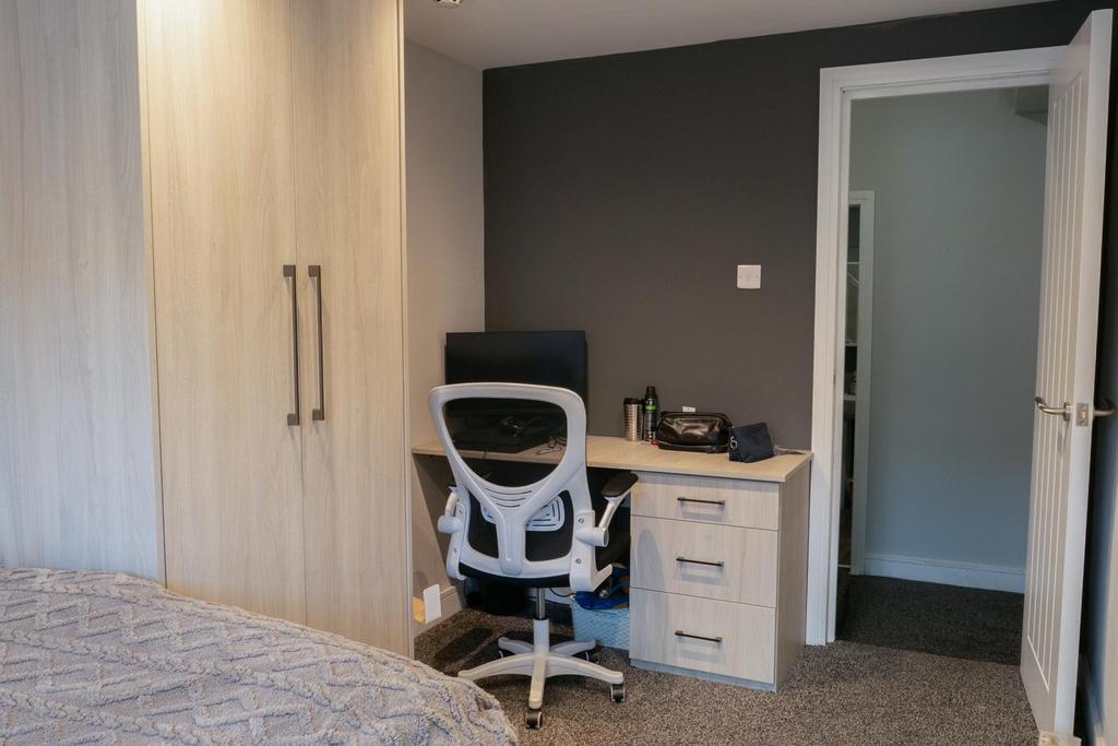 A tidy bedroom featuring a comfortable bed, a d...