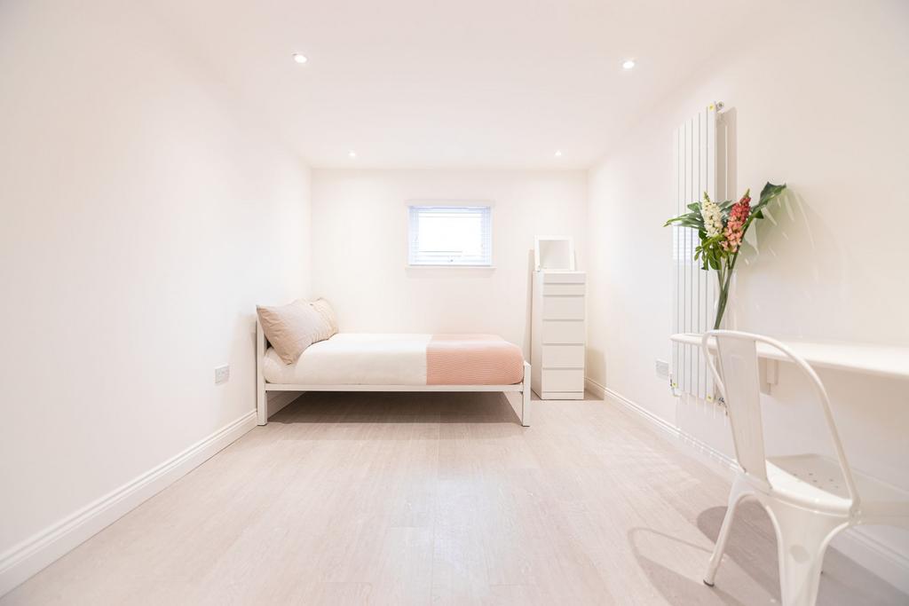 Bright, minimalist single bedroom with pale woo...