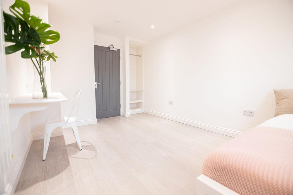 Bright, modern bedroom with pale wood flooring,...