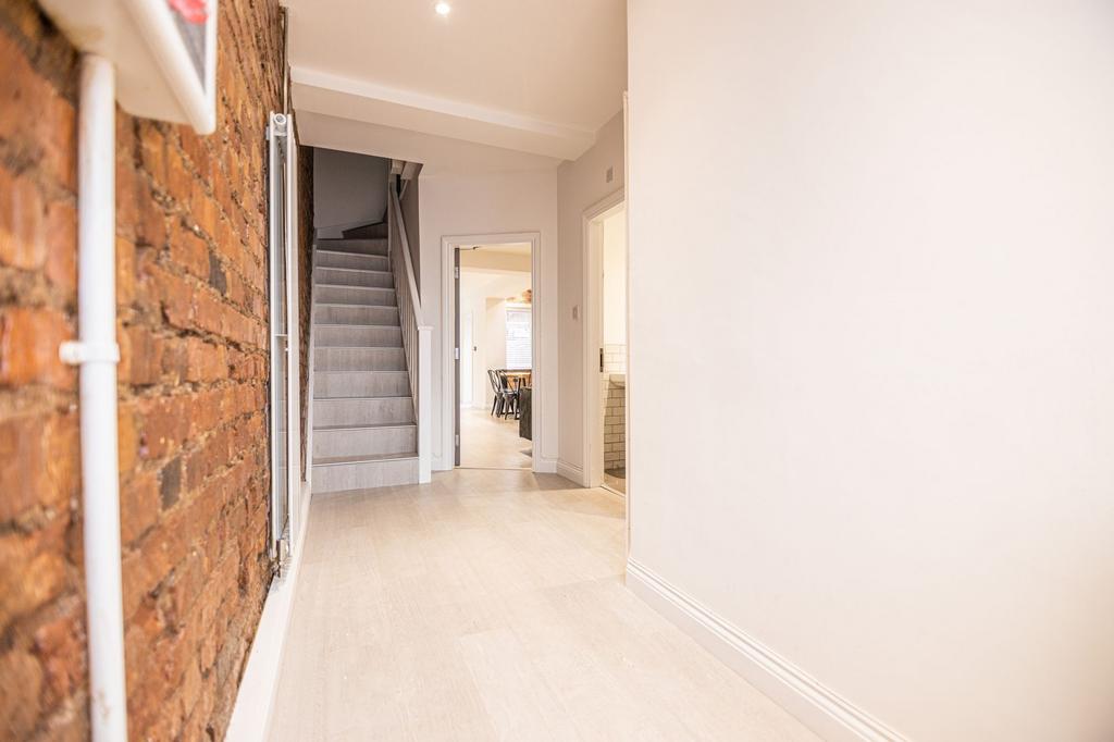 Bright, modern hallway with exposed brick featu...