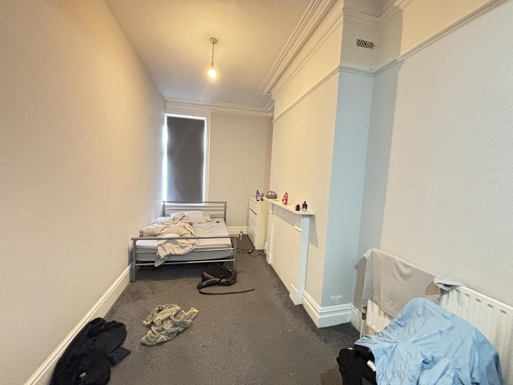A modest bedroom with a single bed and a small ...
