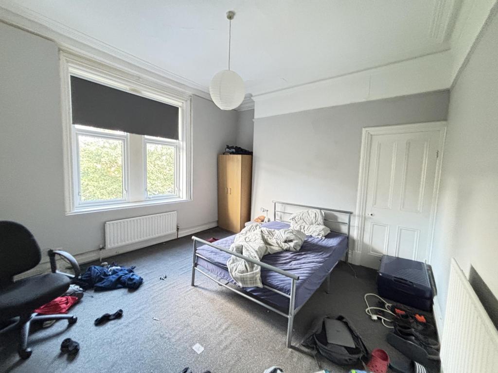 A modest bedroom featuring a single bed with a ...