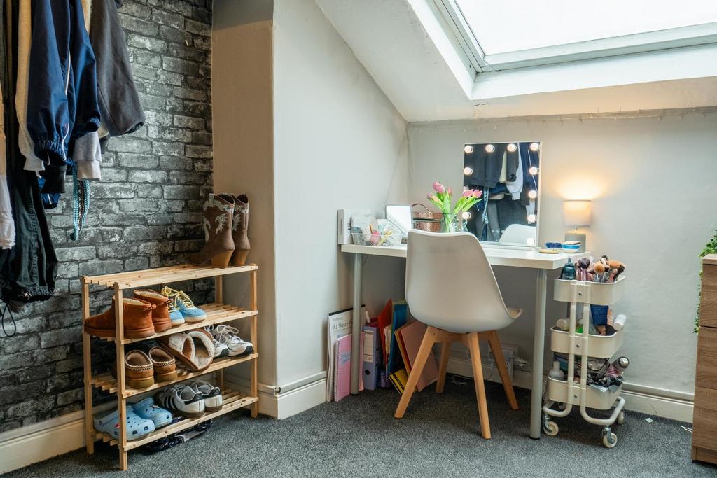 A well-lit bedroom featuring a white desk with ...