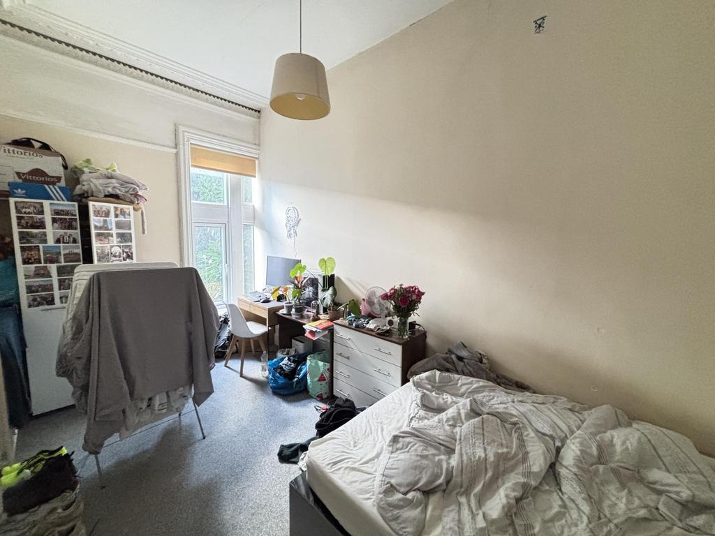 A modest bedroom featuring a bed, some personal...