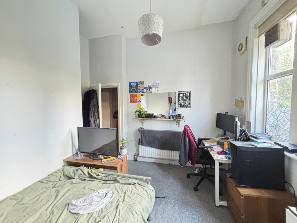 A cozy bedroom featuring a bed, desk, and windo...
