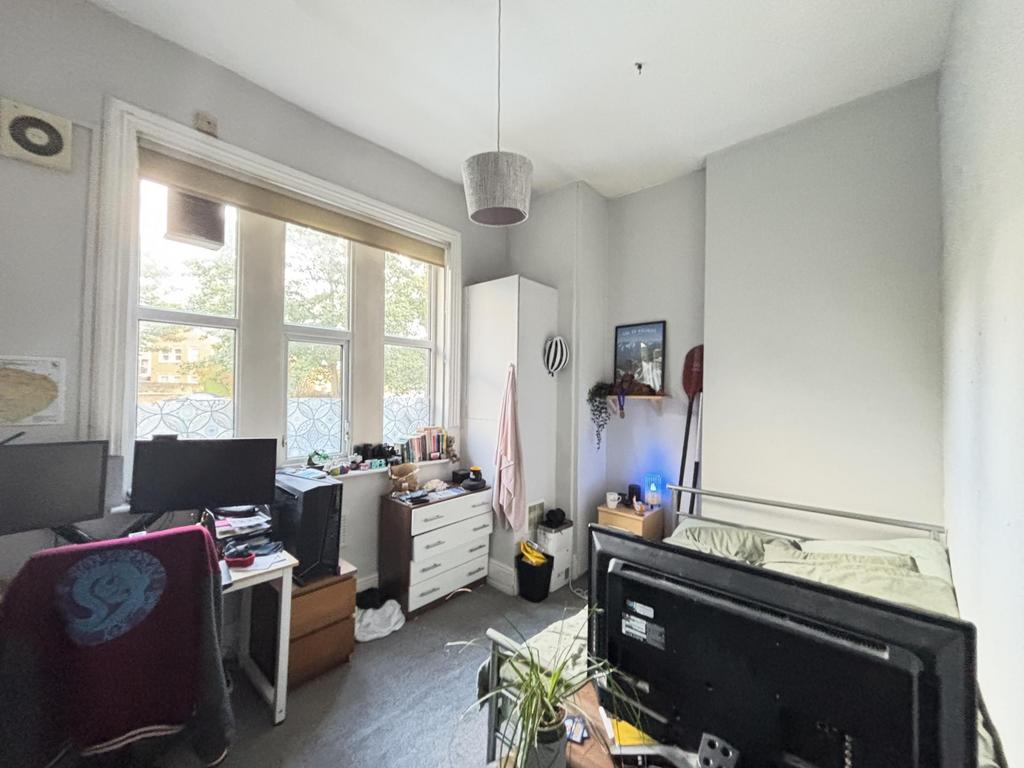 A modest bedroom with a window providing natura...