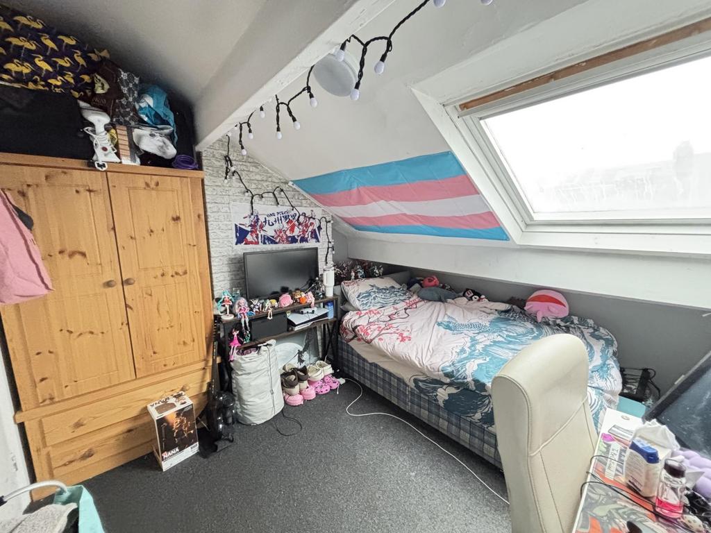A cozy bedroom with a sloped ceiling and a skyl...