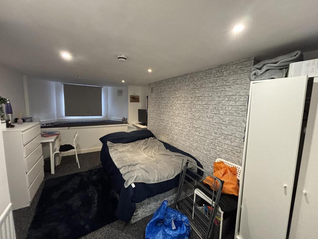 A modest bedroom with a single bed, some storag...