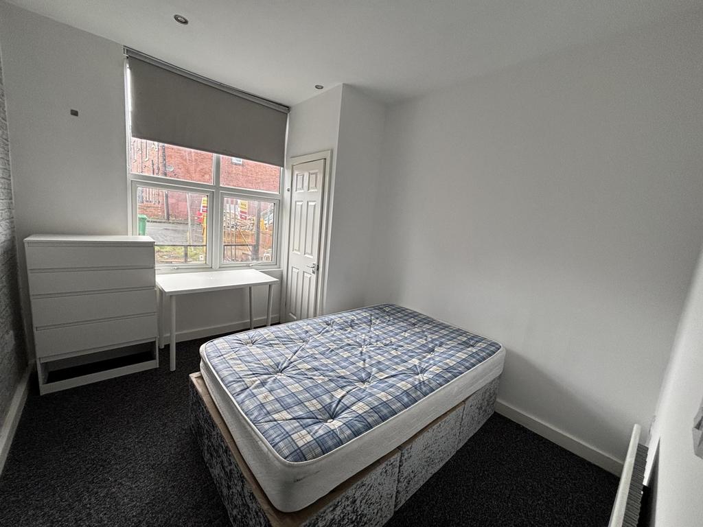 A well-lit single bedroom featuring a comfortab...
