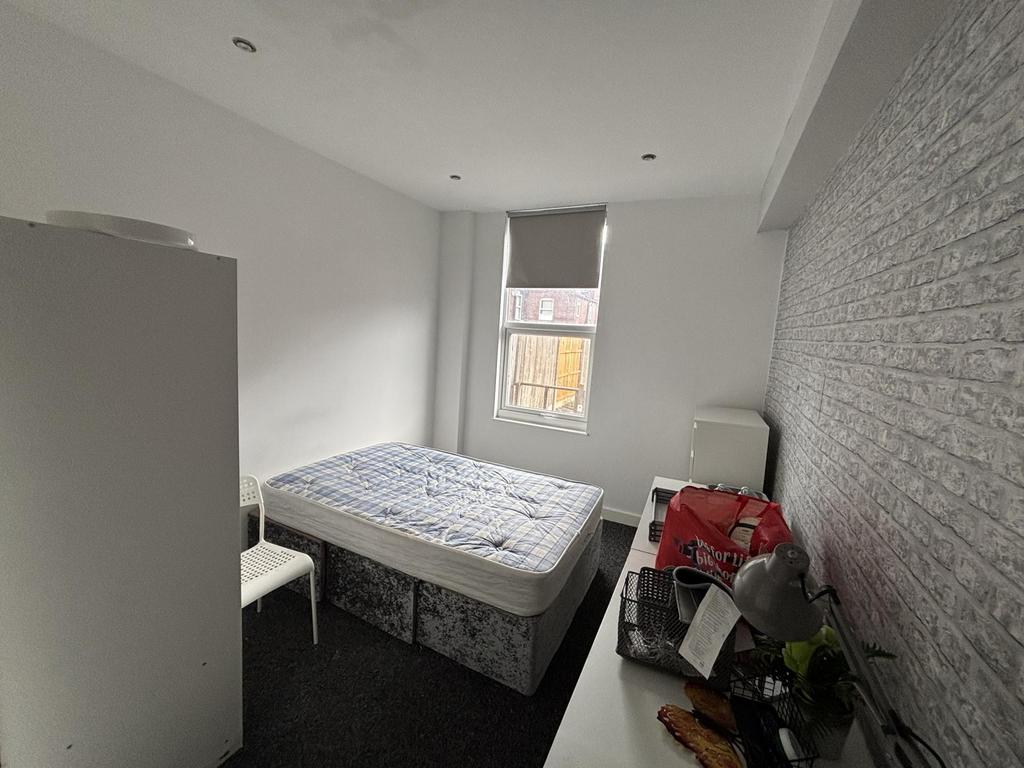 A tidy and well-lit bedroom with a large window...