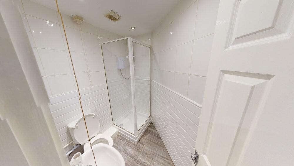 A clean, modern bathroom featuring a shower enc...
