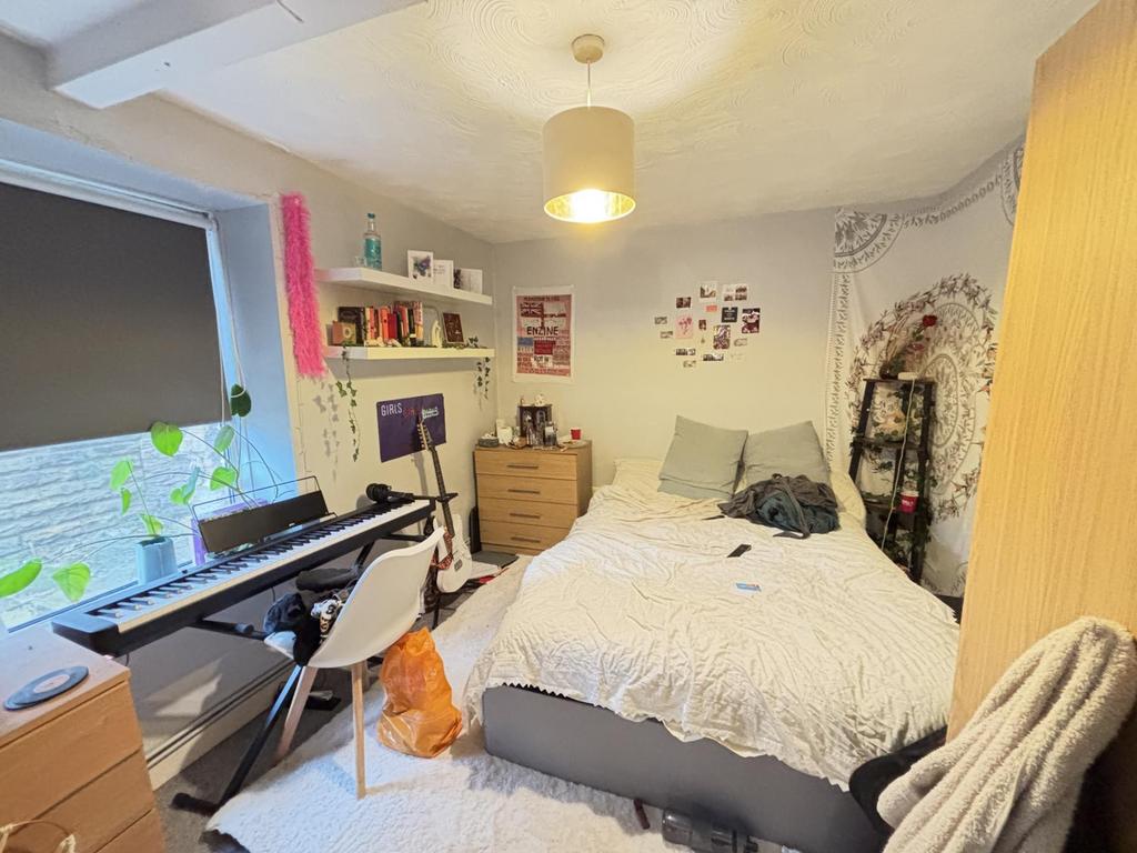 A cozy bedroom featuring a double bed, a desk w...