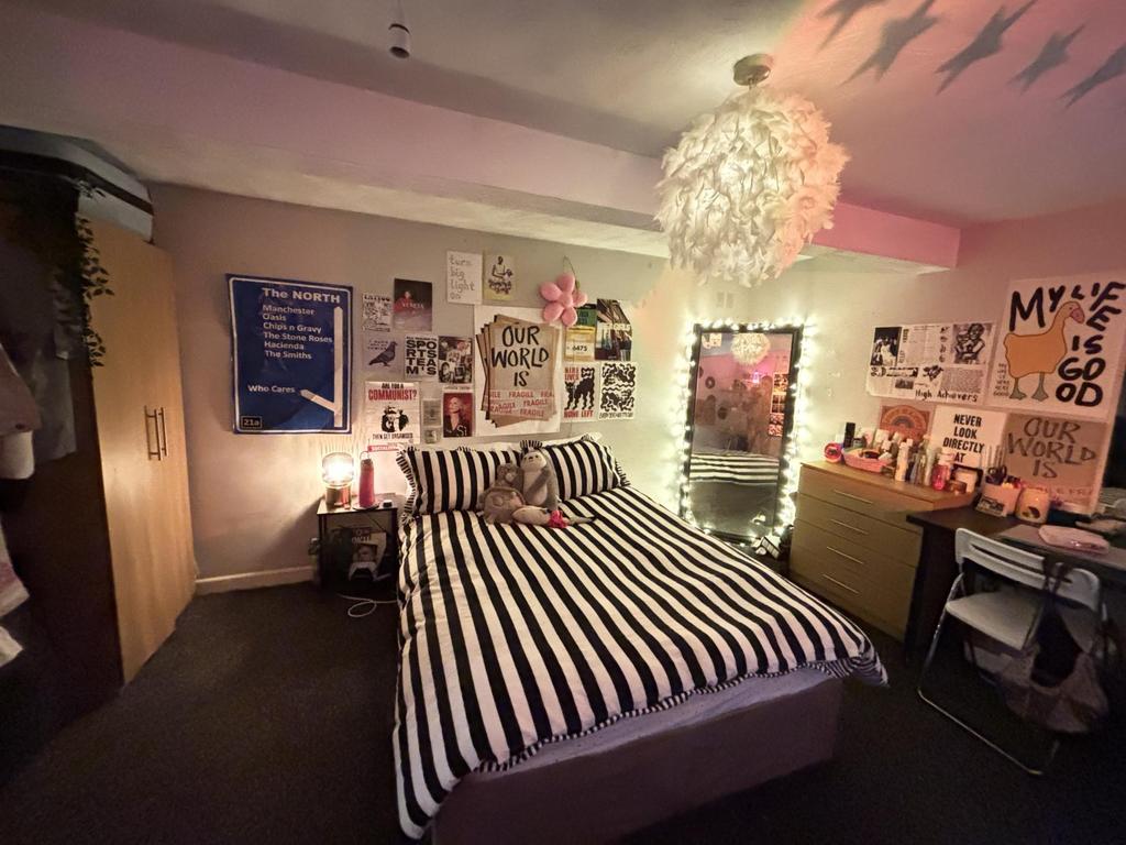 A cozy bedroom featuring a striped bedspread, p...