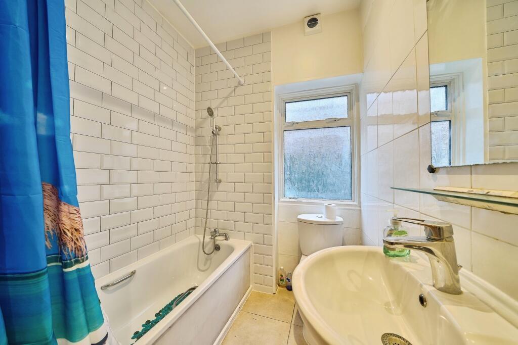 Bright, modern bathroom with a tiled bath and o...