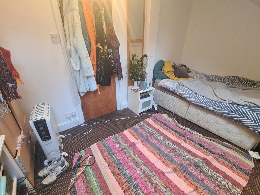 A cozy single bedroom featuring a comfortable b...