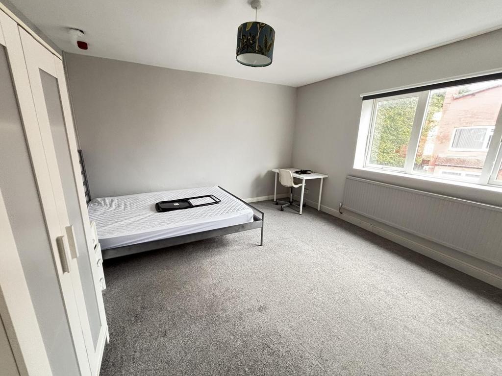 A bright and tidy bedroom with a comfortable si...