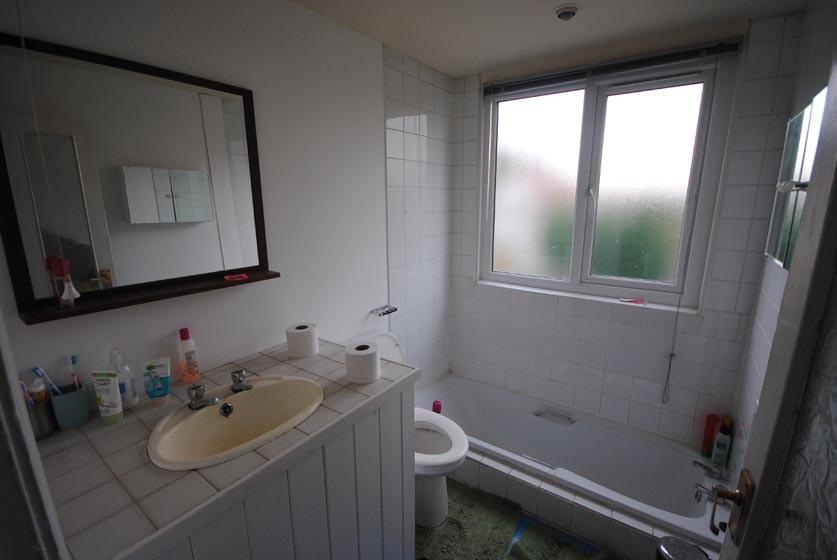 A bright, clean bathroom featuring a bathtub, s...