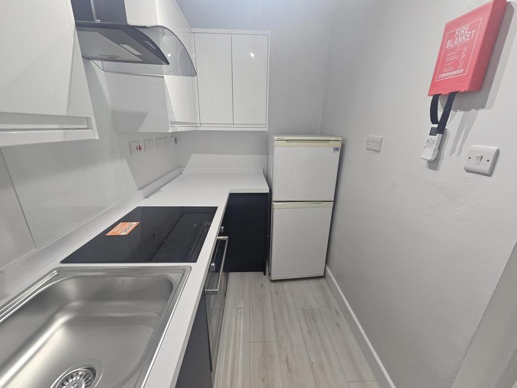 A modern, clean kitchen featuring white cabinet...