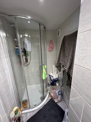 A compact bathroom featuring a curved shower en...