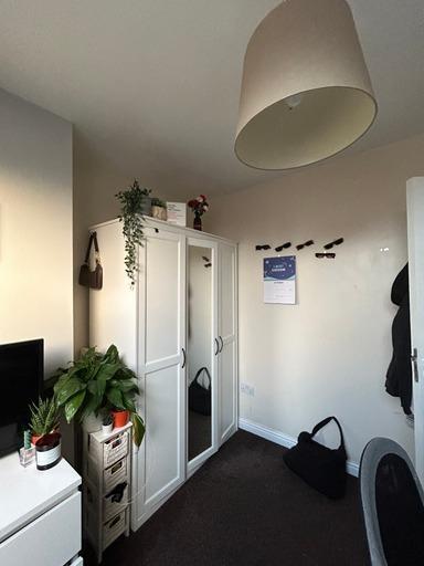 A cozy bedroom featuring a white wardrobe, a sm...
