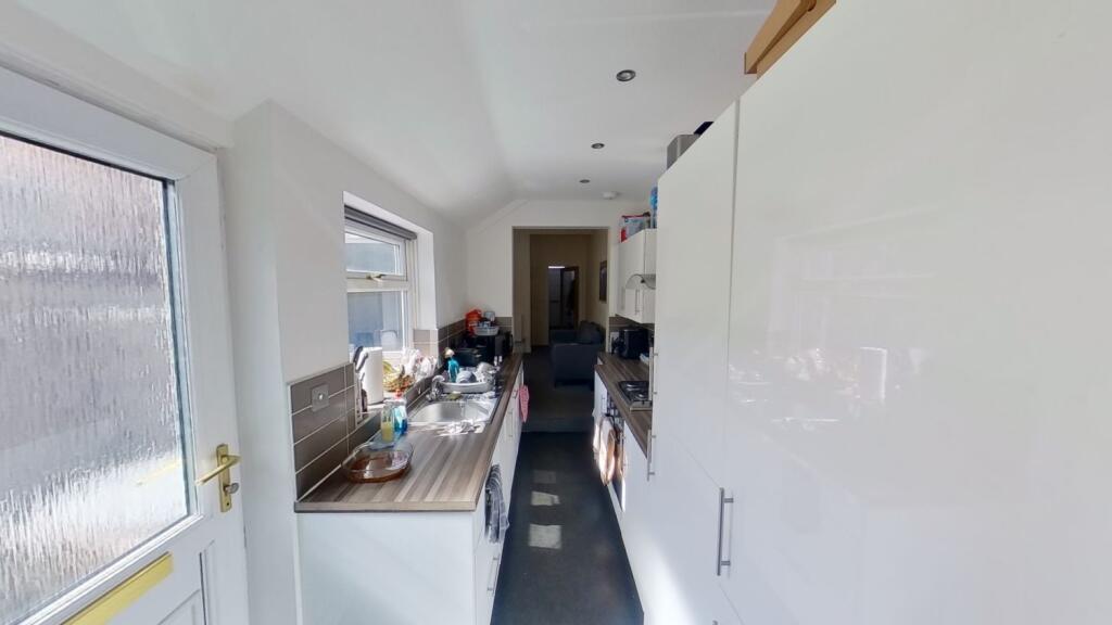 Bright galley-style kitchen with white cabinetr...