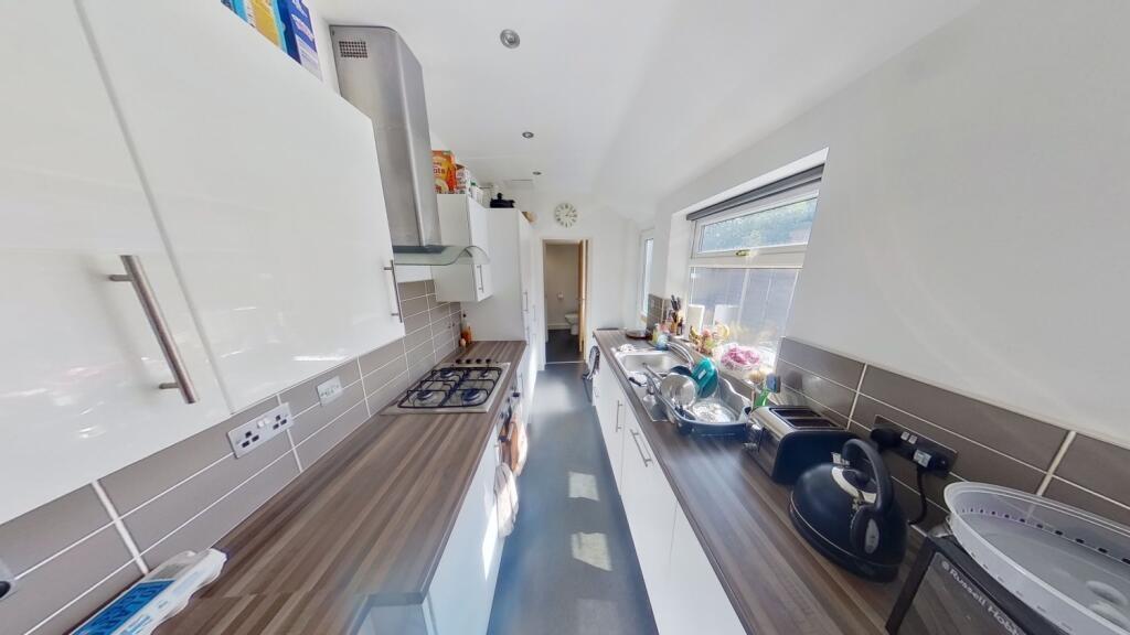Bright, modern galley kitchen with glossy white...