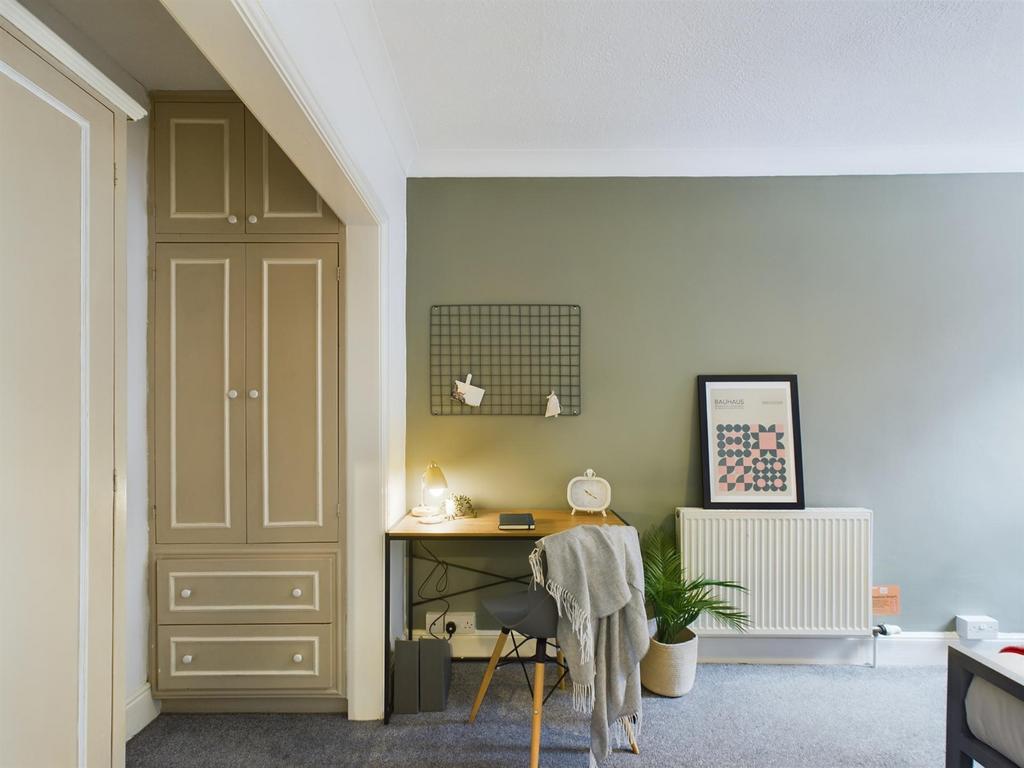 A cozy double bedroom featuring a stylish desk ...