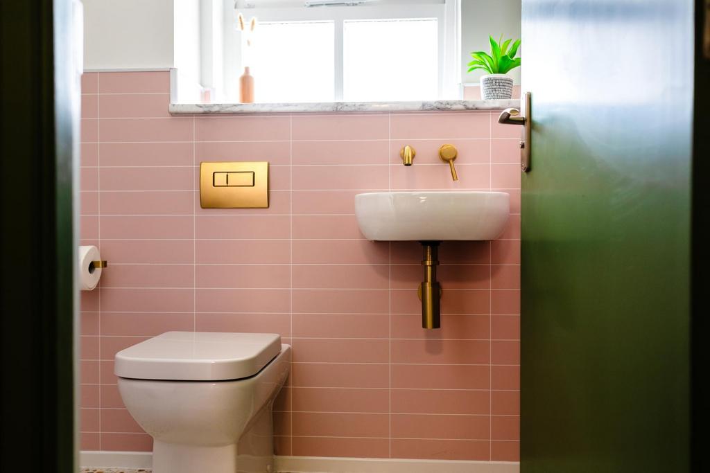 Stylish compact bathroom with pink tiled walls,...