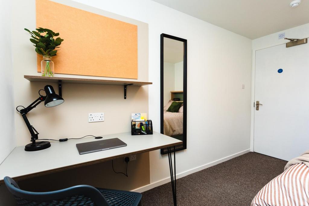 Bright, neatly arranged single bedroom with a w...