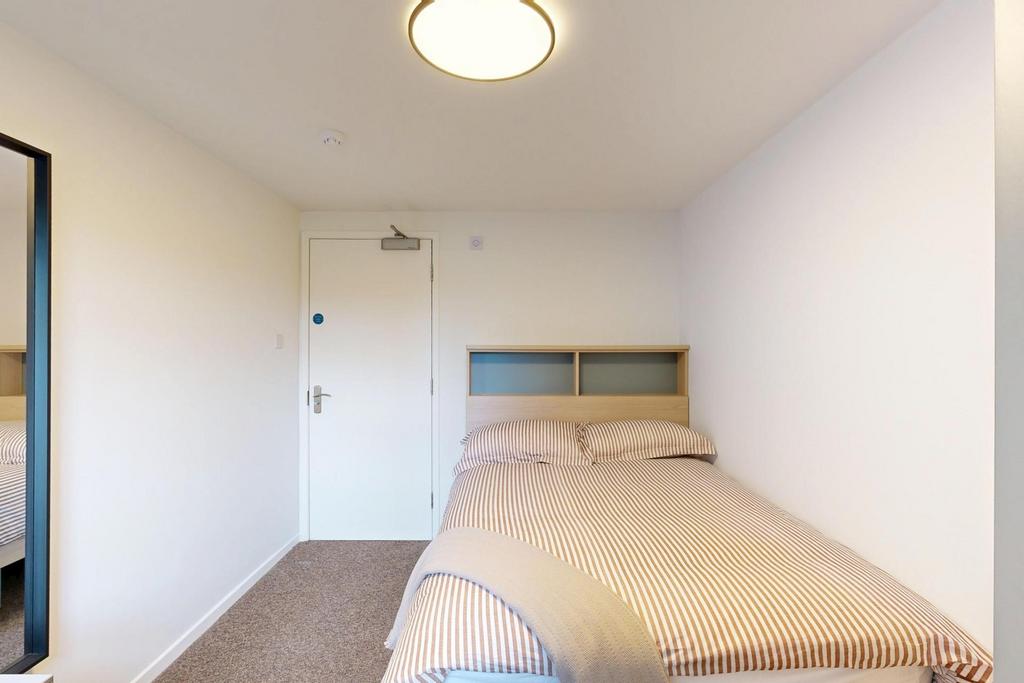 Neat, simply furnished bedroom with a comfortab...