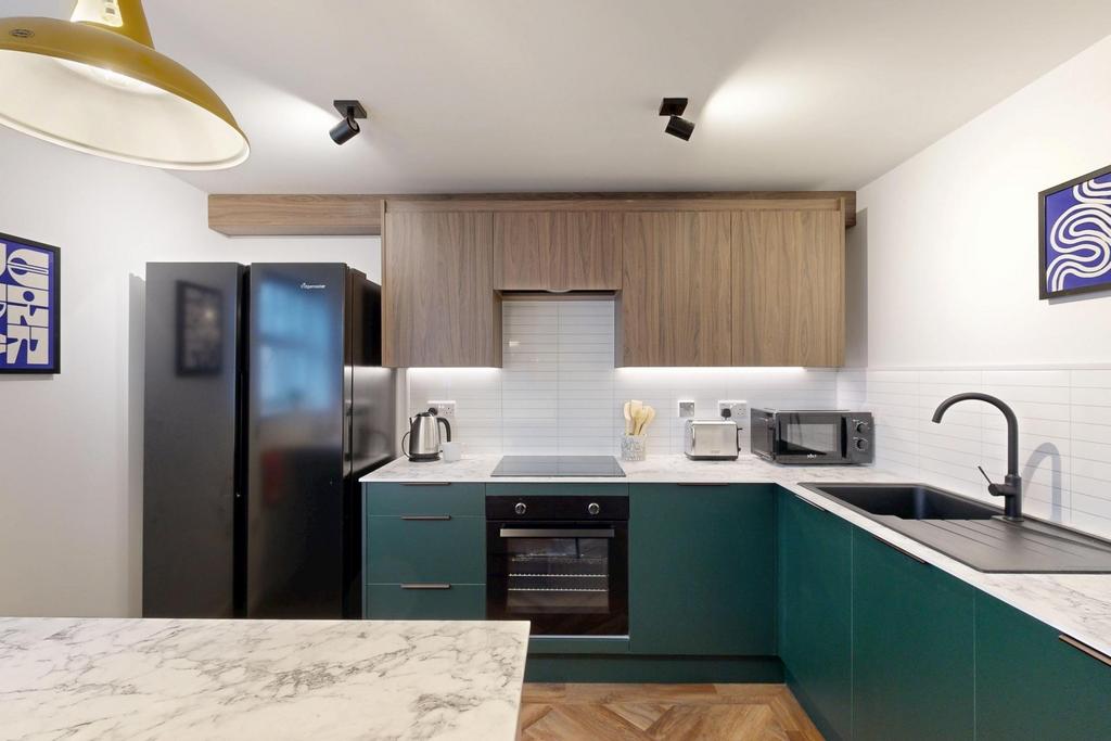 Modern fitted kitchen with teal lower cabinets,...