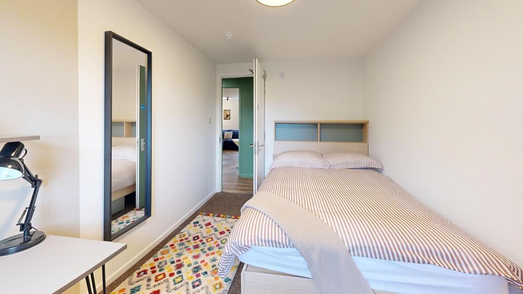 Bright, simply furnished bedroom with a comfort...