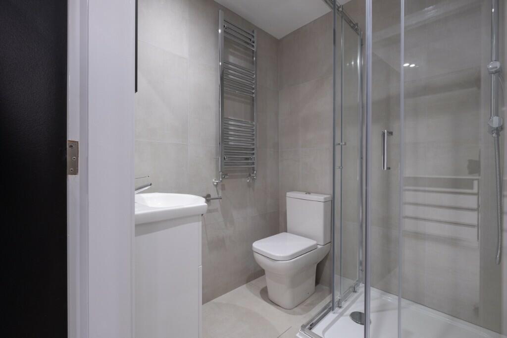 Modern tiled bathroom with a glass-enclosed sho...