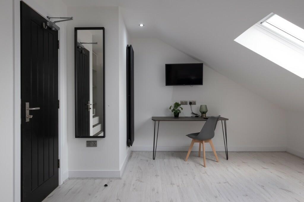 Bright, modern attic bedroom with sloped ceilin...