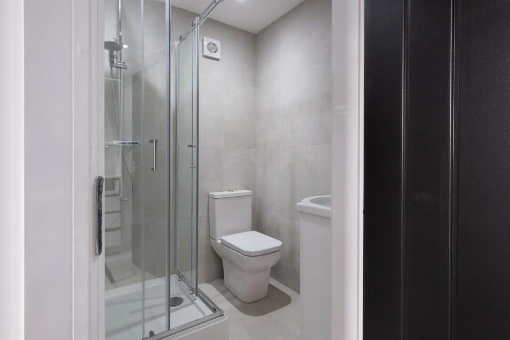 Modern tiled bathroom with a glass-enclosed sho...