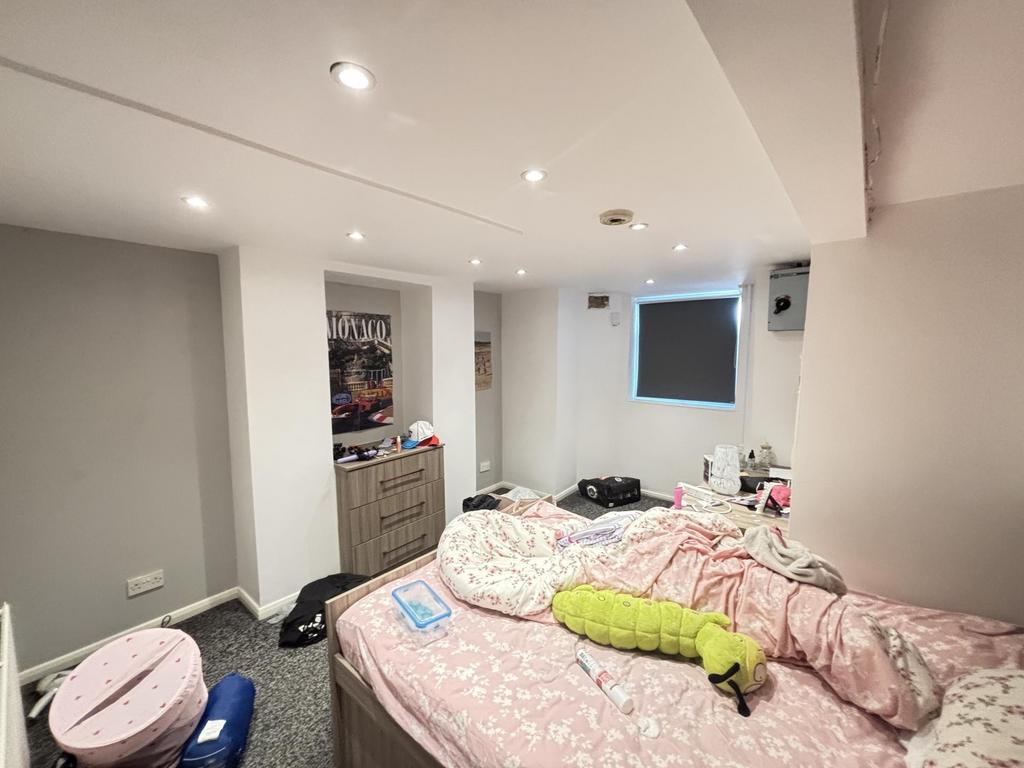 A well-lit bedroom featuring a double bed with ...