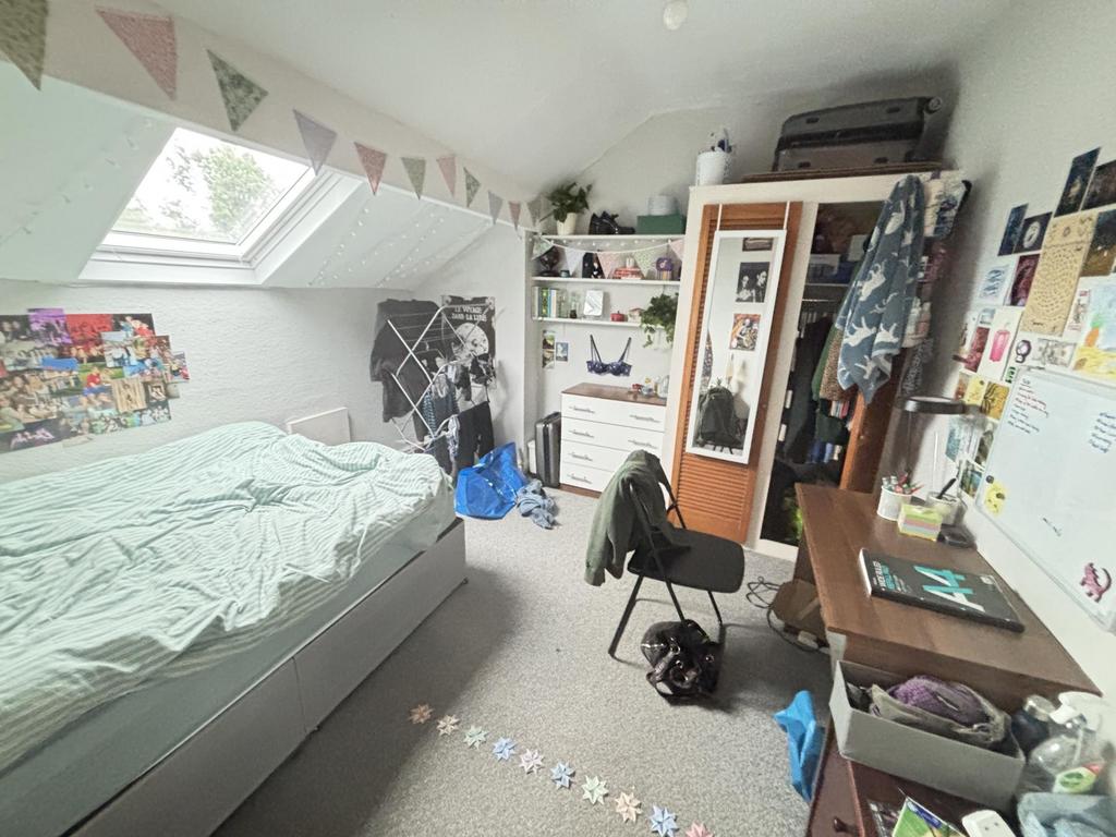 A cozy bedroom with a single bed, a desk, and p...