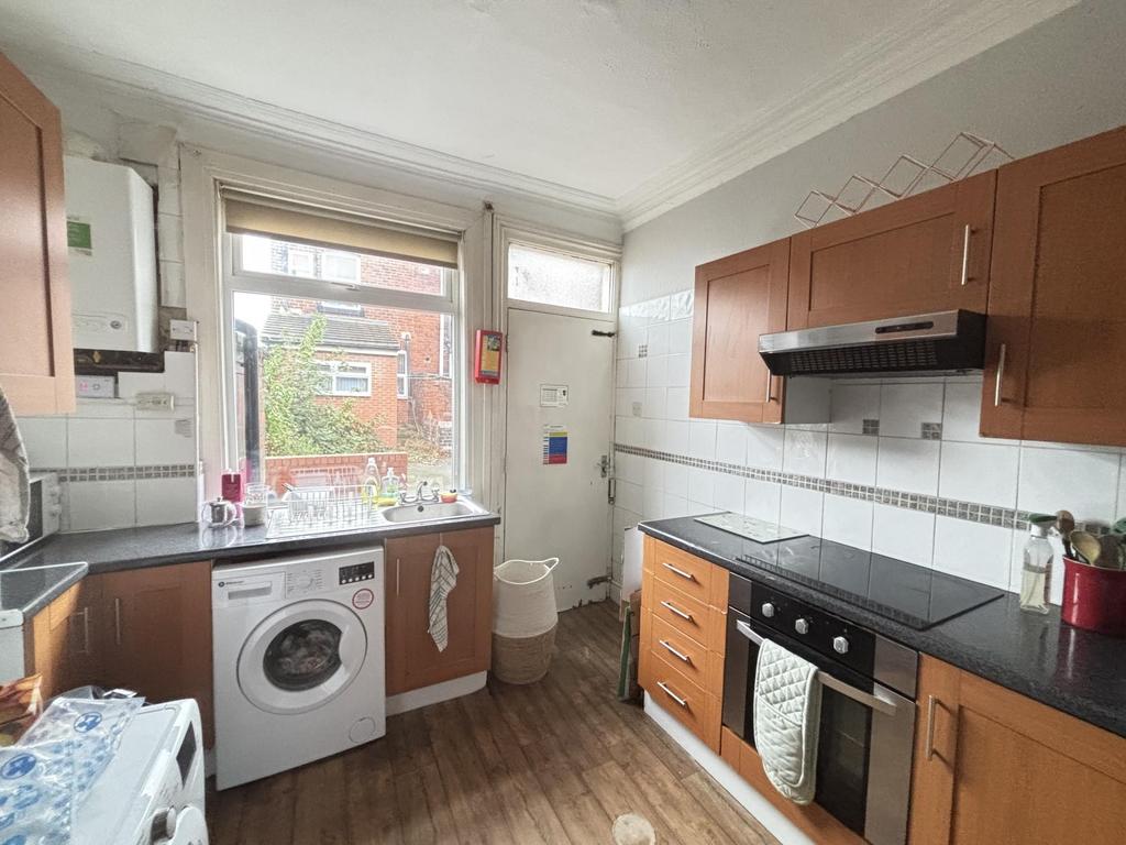 A well-lit kitchen featuring a washing machine,...