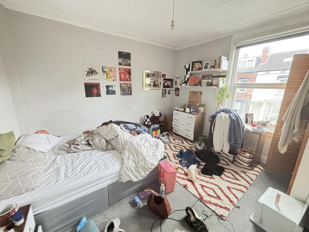 A lived-in bedroom with a bed, clutter on the f...