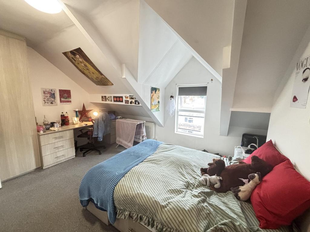 A cozy attic bedroom featuring a neatly made be...