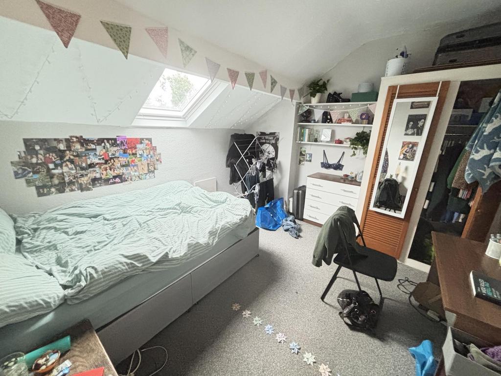A cozy bedroom with a single bed, cluttered wit...
