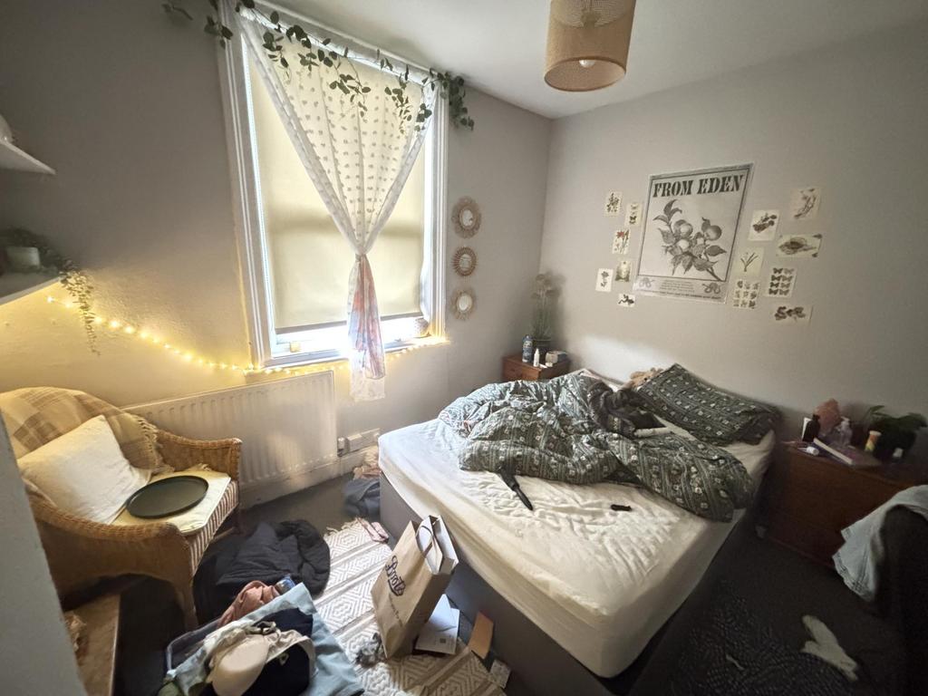 A cozy bedroom with a neatly made double bed, s...